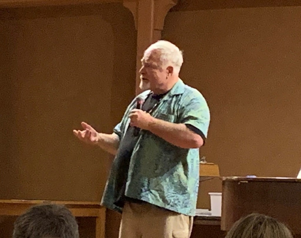 A man gestures on stage while speaking